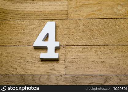 Figure four on a wooden, parquet floor as a background.. Number four on a wooden, parquet floor.
