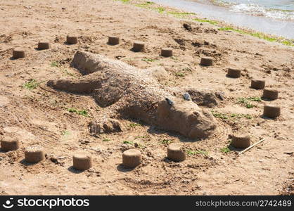 Figure of lizard making by children from sand on sea coast