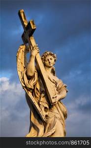 Figure of sad angel carries heavy cross in the evening light