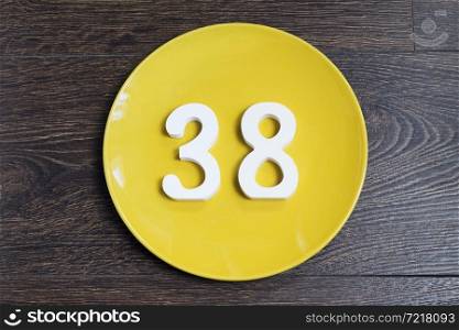 Figure thirty-eight at the plate yellow and brown background.. The number thirty-eight on the yellow plate.