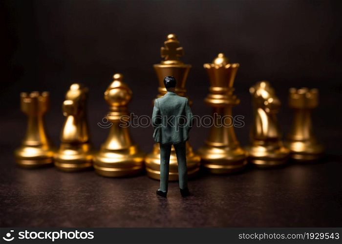 Figures businessman standing in front of the golden chess on black isolated background. Concept of business analysis and strategy. Stepping into the startup, new business player