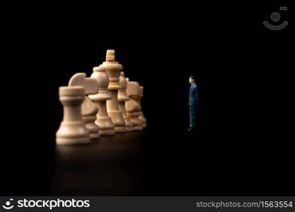 Figures businessman standing in front of wooden chess on black isolated background. Concept of business analysis and strategy. Stepping into the startup, new business player