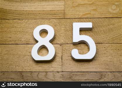 Figures eighty-five on a wooden, parquet floor as a background.. Figures eighty-five on a wooden, parquet floor.