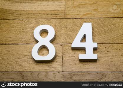 Figures eighty-four on a wooden, parquet floor as a background.. Figures eighty-four on a wooden, parquet floor.