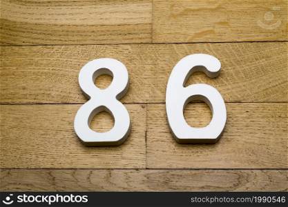 Figures eighty-six on a wooden, parquet floor as a background.. Figures eighty-six on a wooden, parquet floor.