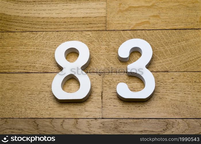 Figures eighty-three on a wooden, parquet floor as a background.. Figures eighty-three on a wooden, parquet floor.