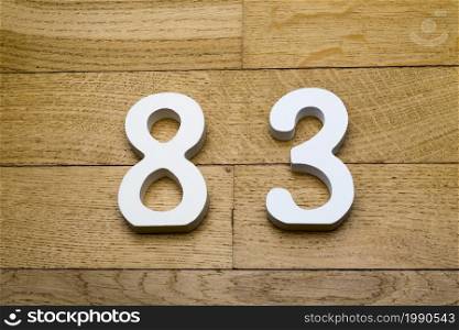 Figures eighty-three on a wooden, parquet floor as a background.. Figures eighty-three on a wooden, parquet floor.