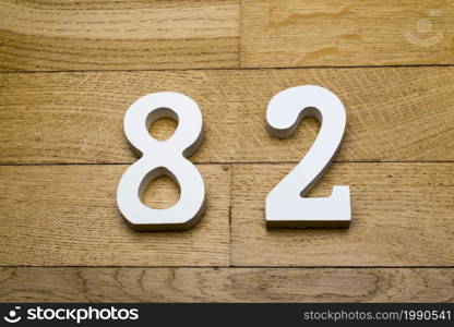 Figures eighty-two on a wooden, parquet floor as a background.. Figures eighty two on a wooden, parquet floor.