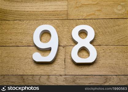 Figures ninety-eight on a wooden, parquet floor as a background.. Figures ninety-eight on a wooden, parquet floor.