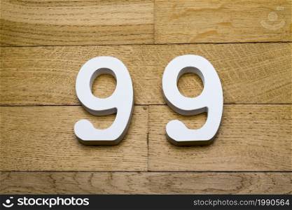 Figures ninety-nine on a wooden, parquet floor as a background.. Numbers ninety nine on a wooden, parquet floor.