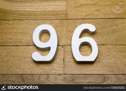 Figures ninety-six on a wooden, parquet floor as a background.. Numbers ninety six on a wooden, parquet floor.
