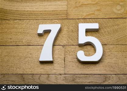Figures seventy-five on a wooden, parquet floor as a background.. Figures seventy-five on a wooden, parquet floor.