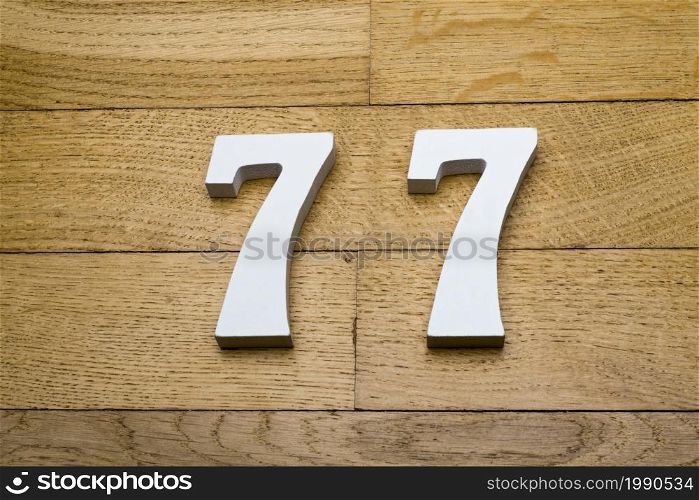 Figures seventy-seven on a wooden, parquet floor as a background.. The figures are seventy-seven on the wooden, parquet floor.