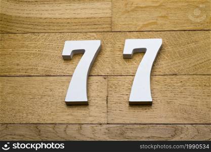 Figures seventy-seven on a wooden, parquet floor as a background.. The figures are seventy-seven on the wooden, parquet floor.