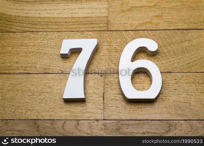 Figures seventy-six on a wooden, parquet floor as a background.. Seventy-six figures on a wooden parquet floor.