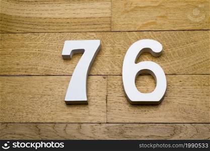 Figures seventy-six on a wooden, parquet floor as a background.. Seventy-six figures on a wooden parquet floor.