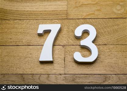 Figures seventy-three on a wooden, parquet floor as a background.. The figures are seventy-three on a wooden, parquet floor.