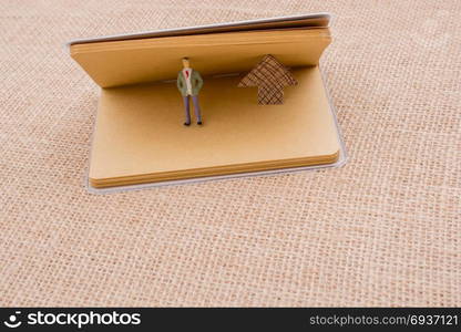 Figurine and an paper arrow in a notebook on canvas