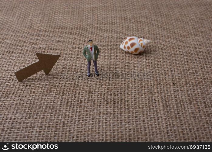 Figurine and arrow sign cut out of brown paper on canvas