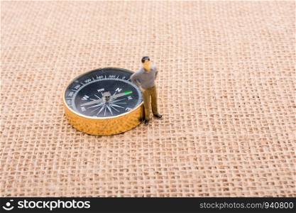 Figurine man beside of a compass on canvas