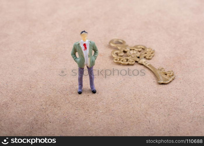 Figurine standing by a retro styled golden color key on a brown background