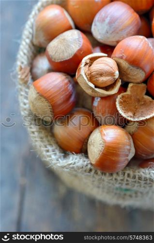 Filbert nut in burlap sack on wooden background