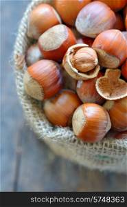 Filbert nut in burlap sack on wooden background