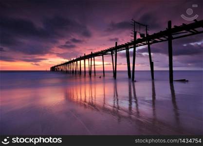 Filed wooden bridge into the sea after sunset on the beach
