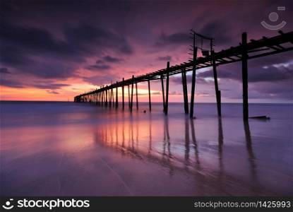 Filed wooden Pier into the sea after sunset on the beach