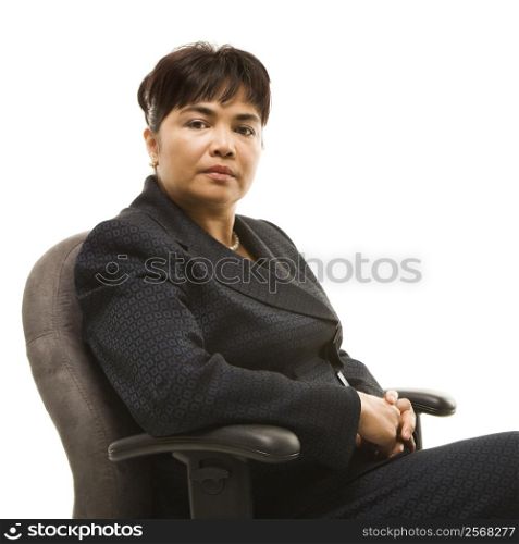 Filipino middle-aged businesswoman sitting in office chair against white background.