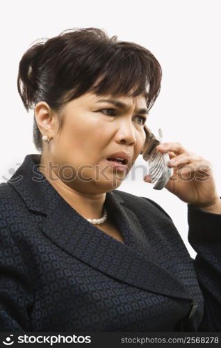 Filipino middle-aged businesswoman talking on cellphone against white background.