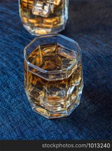 Filled whiskey glasses with ice on a dark background. Two glasses of whiskey with ice
