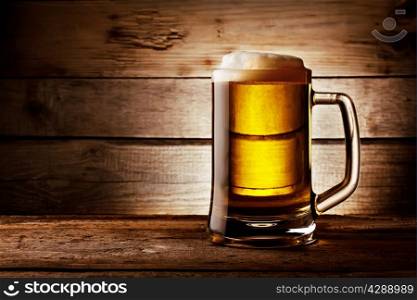 Filled with beer glass with foam on background of wooden planks