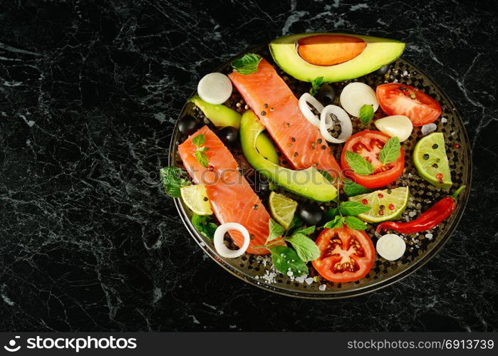 Fillet of red fish and spices on a black background. Free space for text.