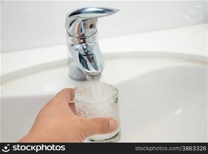 Filling glass of water from stainless steel faucet. Filling glass of water