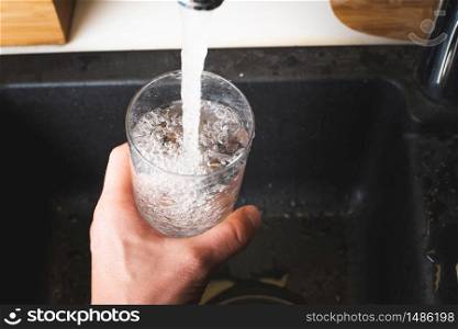 Filling glass of water from stainless steel kitchen faucet. Drinking water concept. Austria pure water from mountains.. Filling glass of water from stainless steel kitchen faucet. Drinking water concept