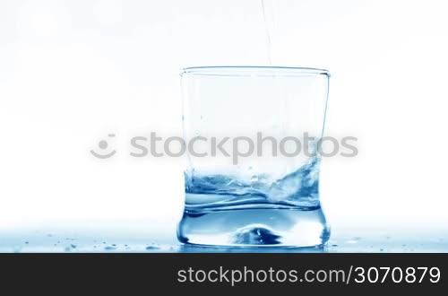 Filling glass with water on white background