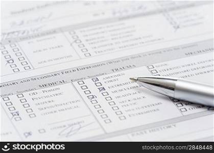 Filling up emergency medical form document pen over chart close-up
