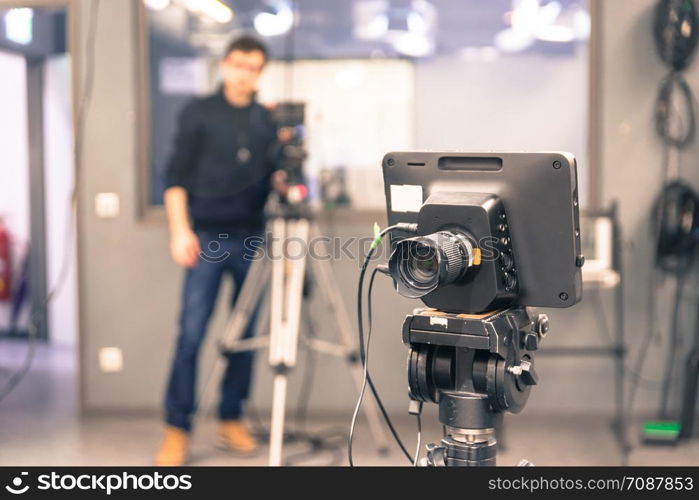 Film camera on a tripod in a television broadcasting studio, cameraman in the blurry background