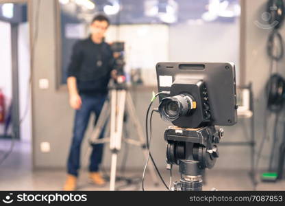 Film camera on a tripod in a television broadcasting studio, cameraman in the blurry background