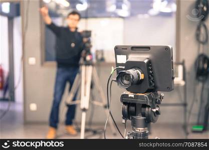 Film camera on a tripod in a television broadcasting studio, cameraman in the blurry background