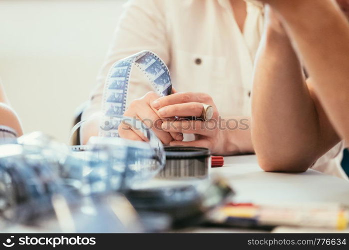 Filmmaker hands holding a film strip, cutting table