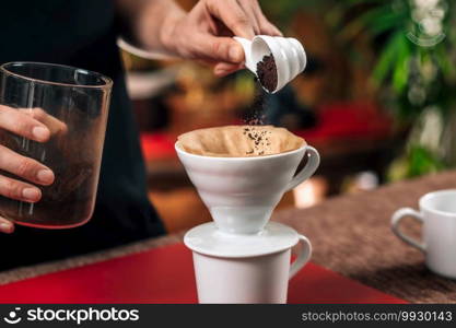 Filter Coffee. Hands of female barista pouring ground coffee into manual coffee dripper