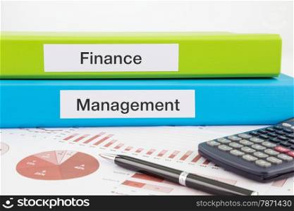 Finance and Management words on labels with document binders, graphs and business reports