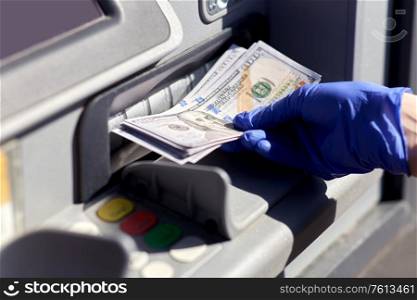 finance, bank and hygiene concept - close up of hand in medical glove with cash money at atm machine. hand in medical glove with money at atm machine