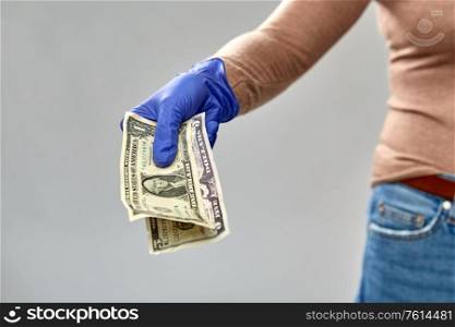 finance, bank and hygiene concept - close up of hand in medical glove with money over gray background. close up of hand in medical glove with money
