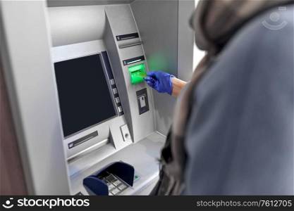 finance, bank and hygiene concept - close up of woman in medical glove with credit card at atm machine. woman in medical glove with credit card at atm
