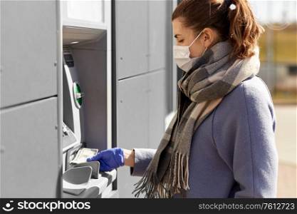 finance, bank and hygiene concept - woman in medical mask and glove with cash money at atm machine. woman in medical mask and glove with money at atm