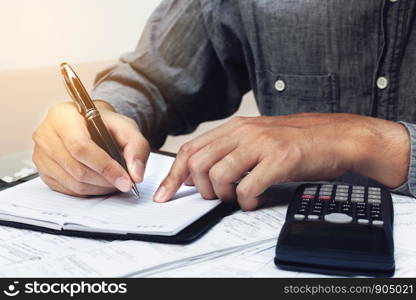 Finance concept. Man writing and make note about cost and expenses at home office.