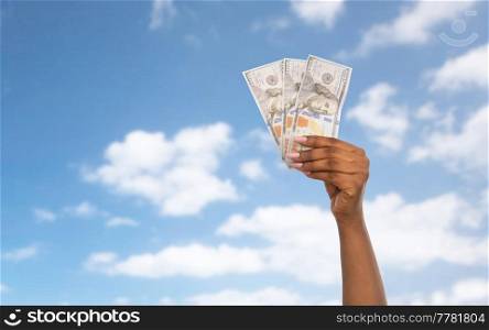 finance, currency and people concept - close up of female hand holding dollar money over blue sky and clouds background. close up of hand with dollar money over blue sky